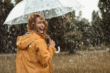 Joyful woman walking in rainy weather